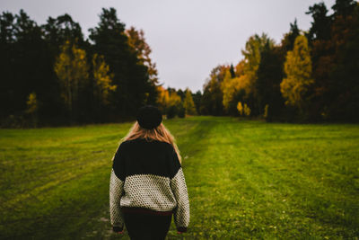 Rear view of woman walking on field