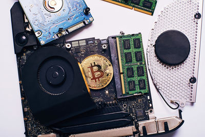 Close-up of bitcoin with computer equipment over white background