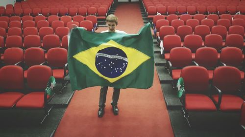 Young man holding flag while standing in auditorium