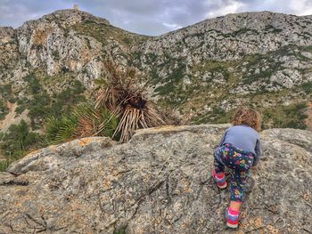 Rear view of girl climbing rock