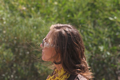 Side view of mid adult woman wearing sunglasses standing against plants