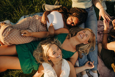 High angle view of cheerful friends laughing while lying down at park