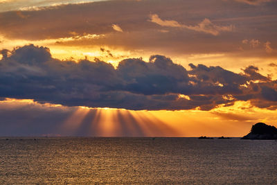 Scenic view of sea against dramatic sky during sunrise