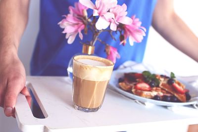 Midsection of person holding drink on table