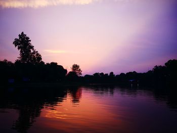 Silhouette trees by lake against sky during sunset