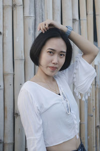 Portrait of beautiful young woman standing against wall