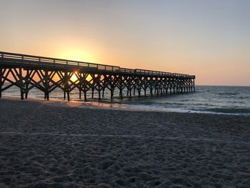 Pier over sea against clear sky during sunset