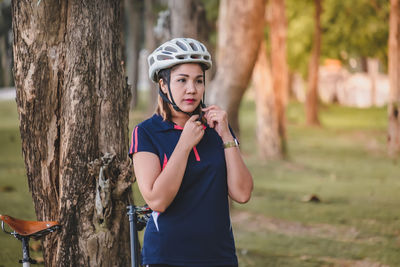 Happy young woman holding tree trunk