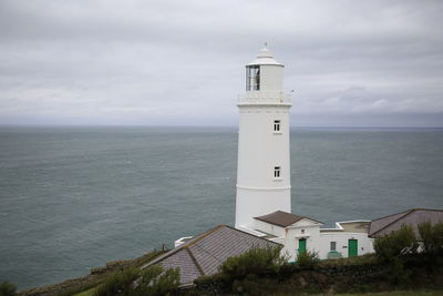 White lighthouse by sea against sky