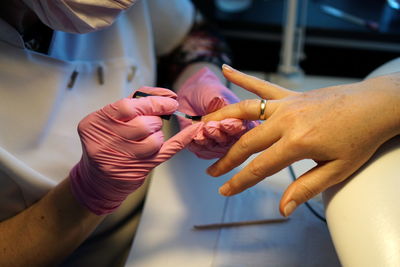 Midsection of beautician applying nail polish on female customer in salon