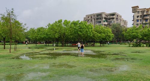 People playing soccer in park against sky