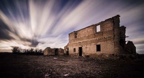 Abandoned and broken building against cloudy sky