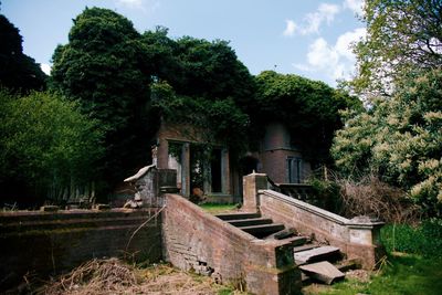 Old abandoned building by trees against sky