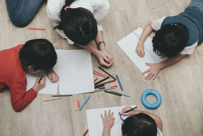 High angle view of mother and children drawing on papers