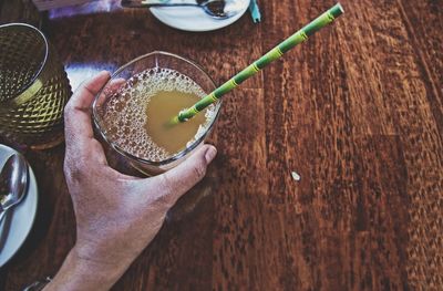 High angle view of hand holding drink on table