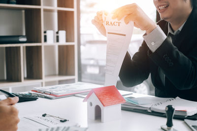 Midsection of man holding paper at table