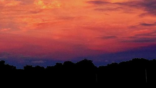 Low angle view of silhouette trees against dramatic sky