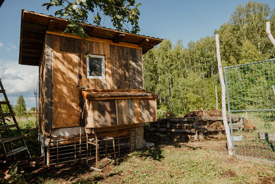 Charming homemade henhouse stands amidst trees on a bright day