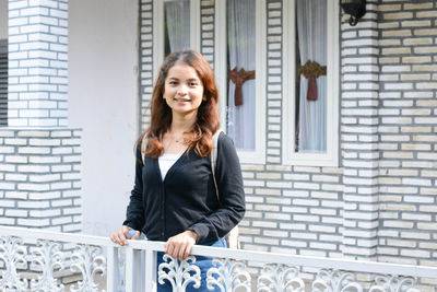 Portrait of smiling young woman standing on brick wall this photo is located in central java indo