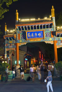 People walking at historic chinese gate at night