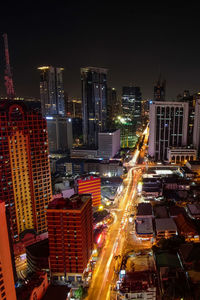 High angle view of illuminated street amidst buildings in city at night