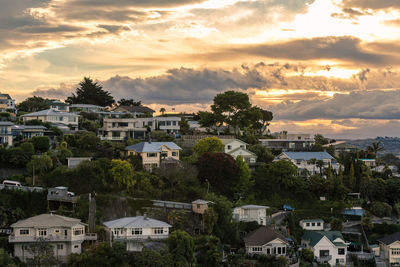 Houses in town against sky at sunset