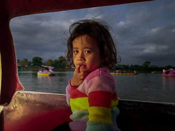 Portrait of young woman standing against lake