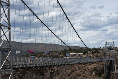 Suspension bridge in city against sky