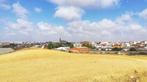 Houses on field by city against sky