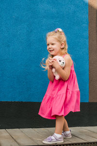 Full length of cute girl standing against wall