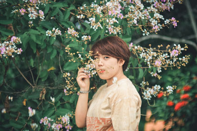 Portrait of beautiful woman standing by flowering plants