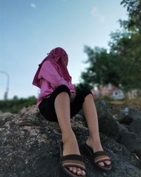 Midsection of woman on rock against sky