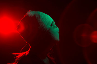 Side view of woman covered with bandage on face against black background