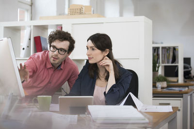 Man and woman discussing at desk in office