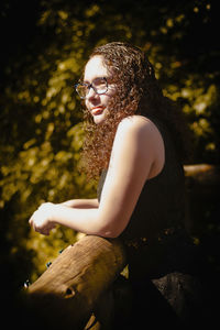 Young woman looking away while standing by railing