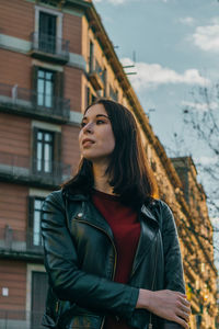 Smiling young woman standing against built structure