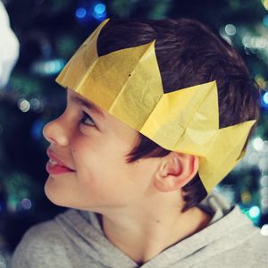 Close-up of smiling boy wearing paper crown at night during christmas