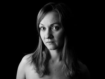 Portrait of young woman against black background