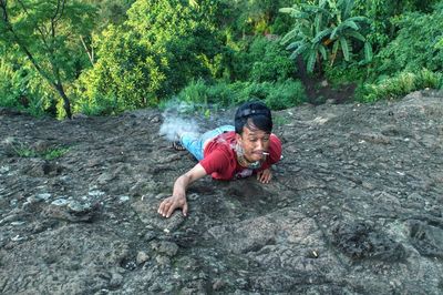 Man smoking cigarette while climbing on rock