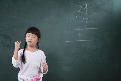 Girl learning mathematics on blackboard