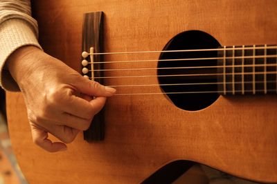 Midsection of man playing guitar