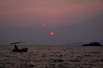 Boats in sea at sunset