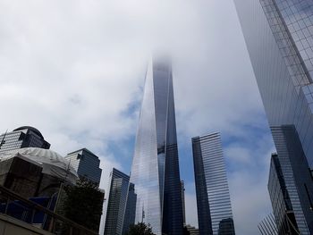 Low angle view of skyscrapers against cloudy sky