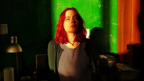 Young woman looking away while standing against wall