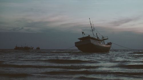 Boat sailing in sea against sky during sunset