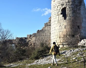 Rear view of woman standing by built structure against sky