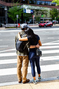 Rear view of two people crossing road