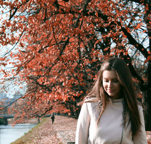 Portrait of beautiful young woman standing by cherry tree