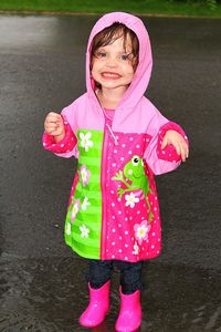 Portrait of cute girl standing on road during rainy season