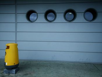 Yellow bollard against wall